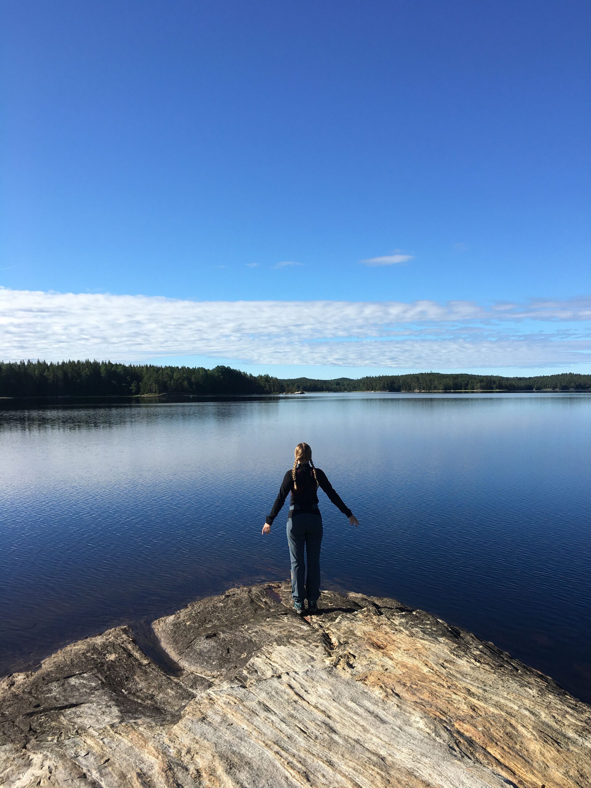 Eine Yogini von hinten, die vor einem See steht