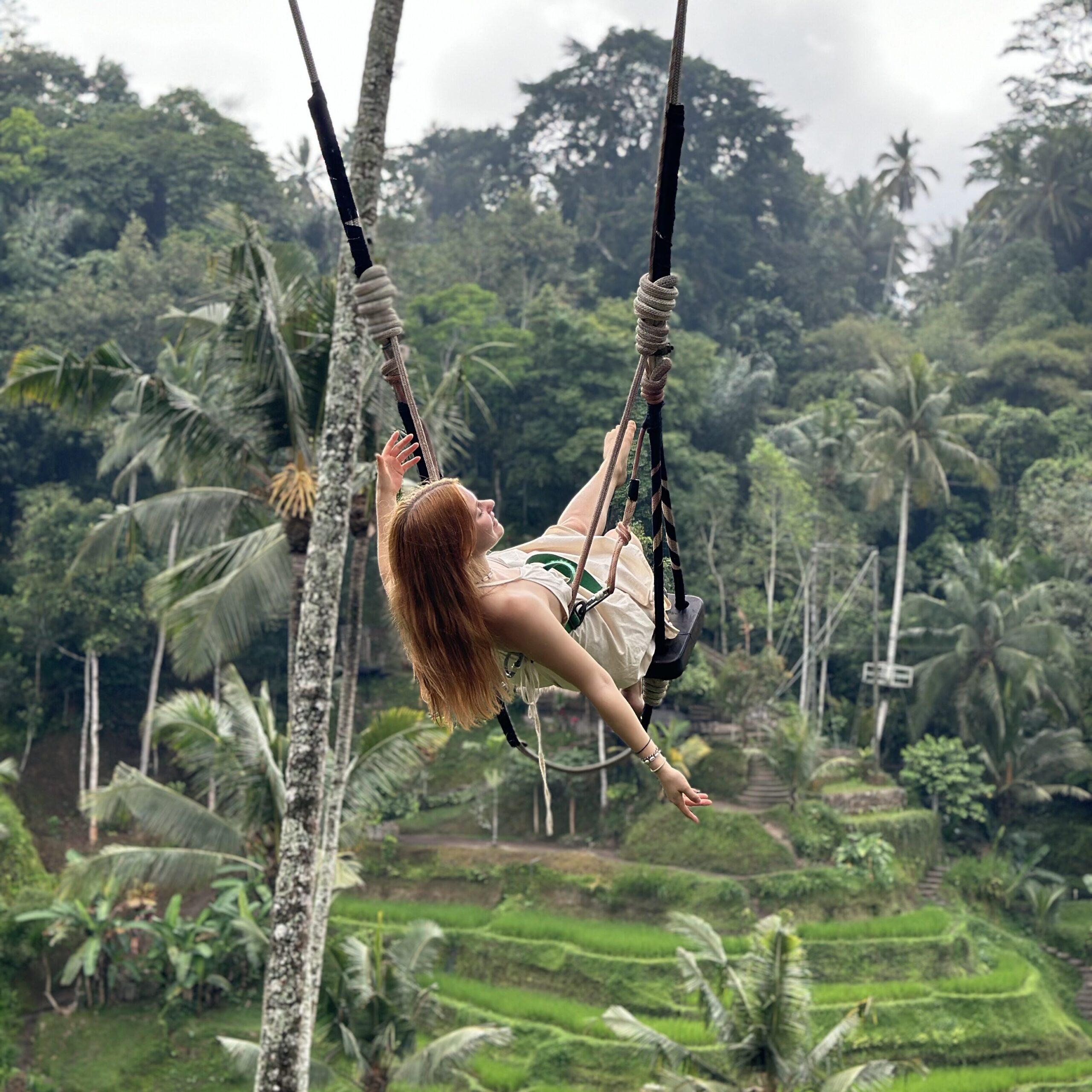 Eine Yogini auf einer Schaukel in den Reisfeldern auf Bali