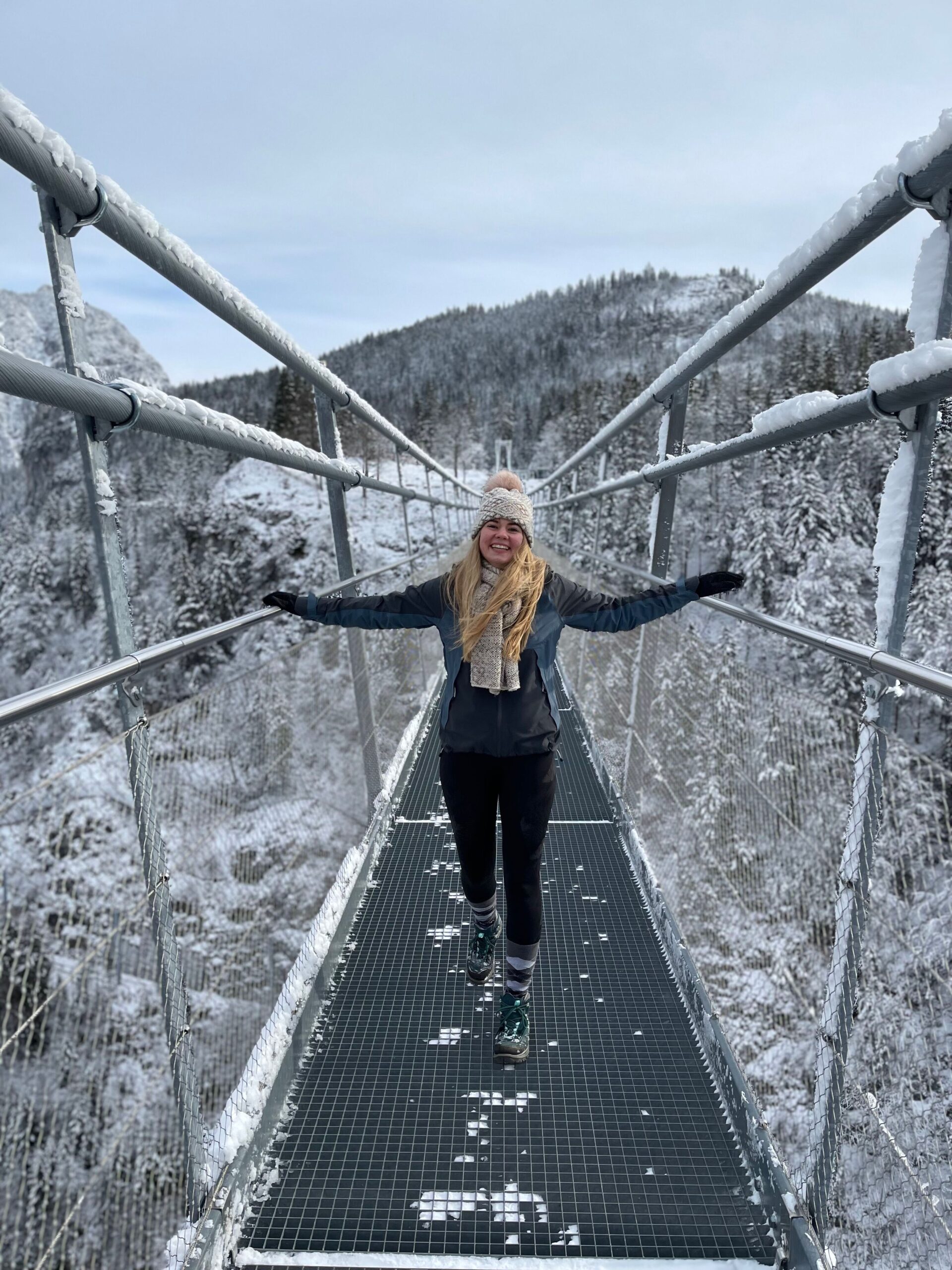 Eine Yogini auf einer Hängebrücke bei Schnee