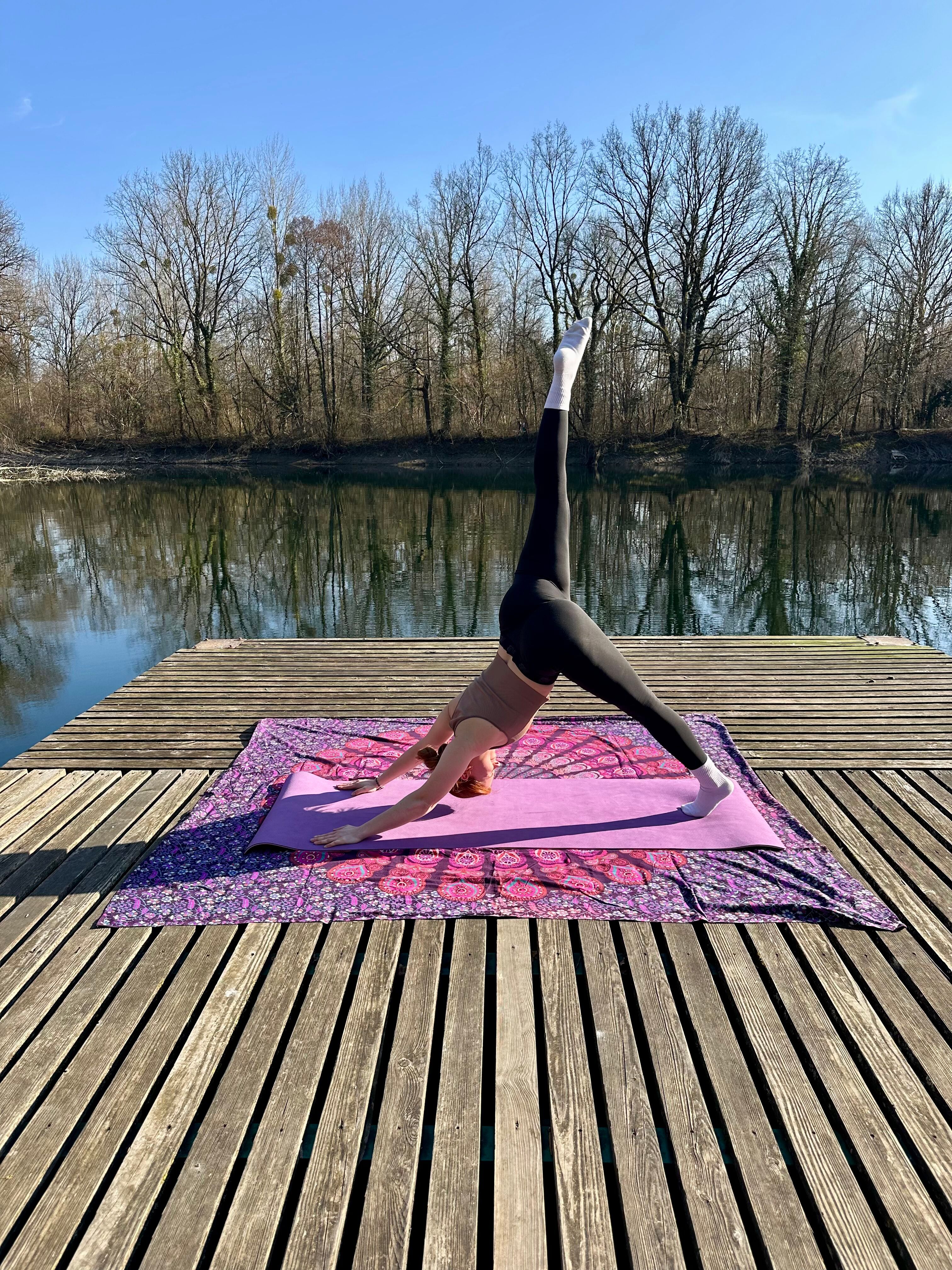 Yogini im dreibeinigen Hund auf einem Floß am Wasser