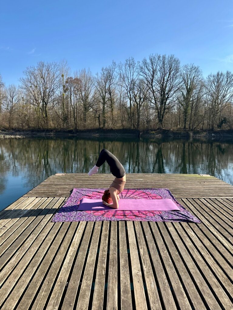 Yogini im Kopfstand auf einem Floß am Wasser