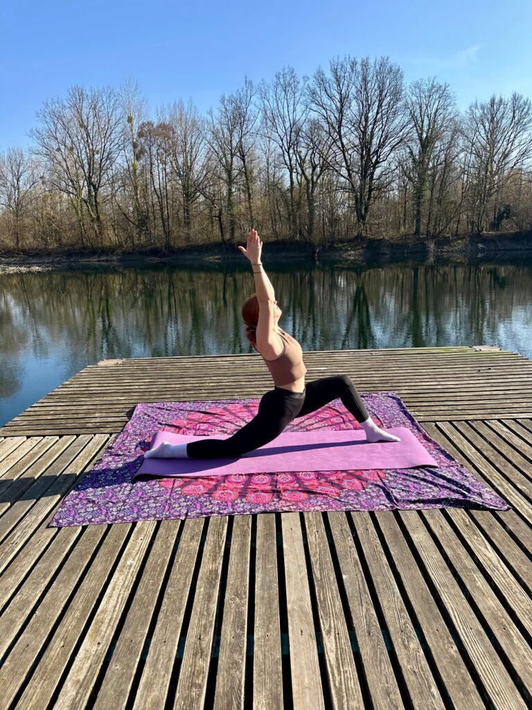 Yogini im Lunge auf einem Floß am Wasser